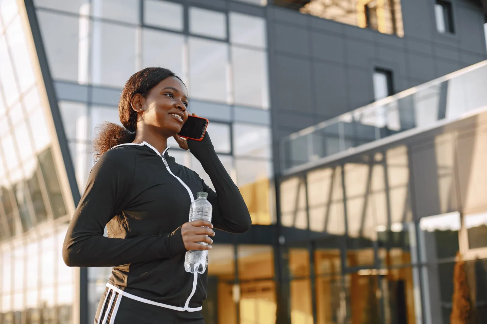 Osoba dzwoniąca w sprawie rezerwacji boiska, na tle rozmytego boiska Orlik