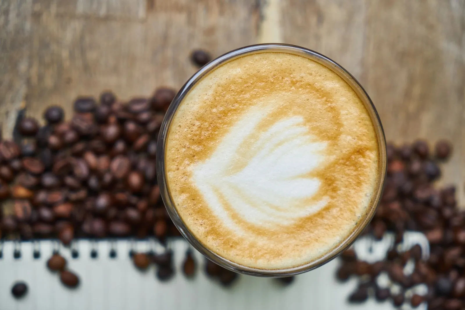Top view of a latte with beautiful latte art and coffee beans, perfect for coffee enthusiasts.